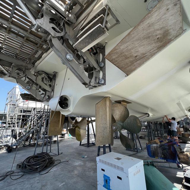 A yacht's hull under maintenance, with scaffolding and tools alongside