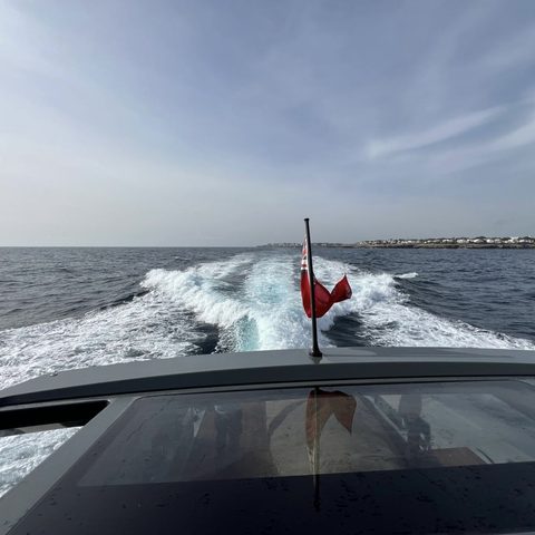 A yacht's bow and ensign under way at sea
